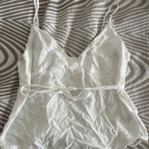 Vit linnetopp med knyt från Primark - Säljer en söt vit linnetopp från Primark i storlek XS. Toppen har smala axelband, v-ringning och en fin knytning i midjan. Materialet är mjukt och lätt, perfekt för varma dagar. Enkel och stilren design som passar till mycket.
