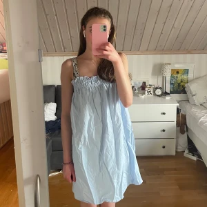 Ljusblå klänning H&M - Säljer en ljusblå klänning från H&M i storlek S. Klänningen har smala axelband, volangdetalj upptill. Den är kort och har en luftig passform, perfekt för varma dagar.