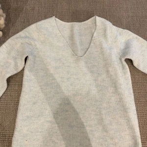 Ljus turkos stickad tröja från Vila - Supermjuk ljus turkos stickad tröja från Vila med v-ringning och långa ärmar. Tröjan har en enkel, ribbad struktur och är perfekt för lager-på-lager. Snygg och enkel att matcha till olika outfits.