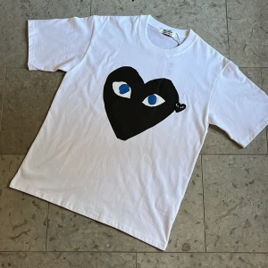 Vit Cdg Play t-shirt - Säljer denna vita t-shirt från Cdg Play med stort svart tryck på bröstet samt broderad logga bredvid, storlek M och superskick. Fraktas inom 24h✅