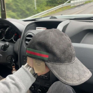 Svart Gucci keps med GG-mönster - Svart keps från Gucci med klassiskt GG-monogram över hela kepsen och ikoniska gröna och röda ränder på sidan. Snygg böjd skärm och justerbar passform. Tillverkad i Italien, materialet är bomull. Perfekt för dig som vill ha en lyxig och stilren accessoar. Den är väldigt solblekt där av billiga priser