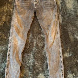 Replay Hyperflex Anbass grå jeans - Slim fit jeans från Replay Hyperflex Anbass i en snygg grå tvätt. Jeansen har klassisk femficksdesign, svarta detaljer och stretchigt material som ger skön passform. Perfekta för dig som gillar en modern och stilren look.