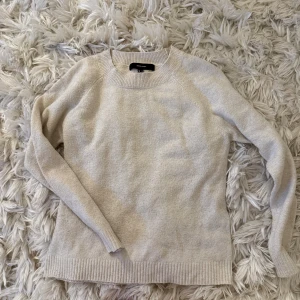 Beige stickad tröja från Vero Moda - Mysig beige stickad tröja från Vero Moda i storlek M. Tröjan har rund halsringning, ribbade muddar och är långärmad. Perfekt för lager-på-lager och enkel att matcha med jeans eller kjol.