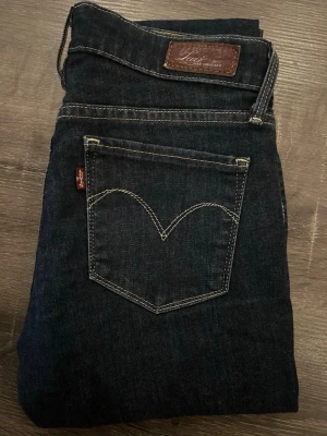 Levi's mörkblå jeans straight fit - Mörkblå jeans från Levi's med klassisk femficksdesign och raka ben. Snygga kontrastsömmar och läderpatch bak i midjan. Perfekta till en avslappnad stil och tillverkade i slitstarkt bomullsjeans.