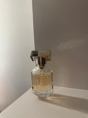 Hugo boss dam parfym ”her” 30 ml.  - Hugo boss dam parfym i ”her” 30 ml. Elegant parfym från Hugo Boss i en genomskinlig, facetterad glasflaska med silverfärgat lock. Doften har en ljusgul ton och flaskan har en lyxig och modern design som passar perfekt på sminkbordet.