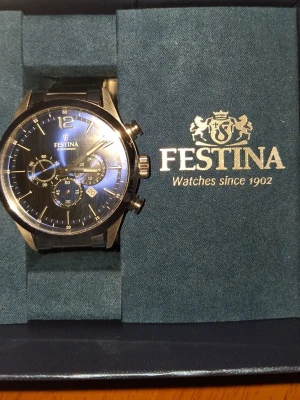 Festina herrklocka med blå urtavla - Snygg herrklocka från Festina med blå urtavla och silverfärgade detaljer. Klockan har kronograf-funktion, tre små urtavlor och svart armband. Kommer i originalask med Festina-logga. Perfekt accessoar för dig som gillar stilrena och moderna klockor.