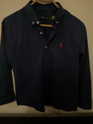 Mörkblå polo skjorta - Mörkblå polo Ralph lauren skjorta i storlek M, passar S också. Inte använd mycket men lite små fläckar som går bort i tvätten.