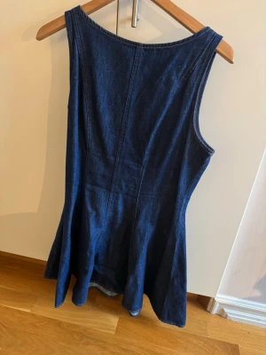 Mörkblå ärmlös jeansklänning - Klänning i jenasmaterial som är utsväng i modellen.  