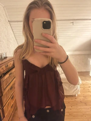 Vinröd volangig linnetopp - Säljer en vinröd linnetopp med volangdetaljer och tunna axelband. Toppen har en luftig och flowy passform, perfekt för varmare dagar. Materialet känns lätt och svalt mot huden.