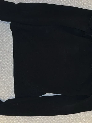 Svart offshoulder-blus med volang - Snygg svart offshoulder-blus från NLY Trend i storlek S. Blusen har långa ärmar och en bred volang runt axelpartiet som ger en trendig look. Tillverkad i ett mjukt och stretchigt material som sitter bekvämt på kroppen.