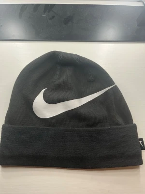 Svart Nike mössa med vit logga - Snygg svart mössa från Nike med stor vit Swoosh-logga framtill och Dri-FIT-material som andas. 