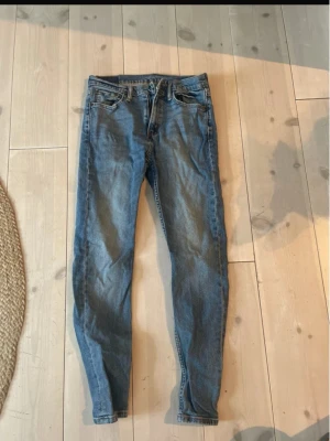 Levi's blå jeans herr - Säljer ett par klassiska blå Levi's jeans i slim fit.  normal midja och raka ben. Tillverkade i mjukt bomullsjeansmaterial med den ikoniska Levi's-lappen bak. Perfekta för dig som gillar en tidlös och clean look.