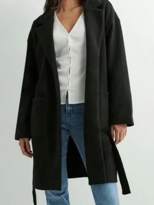 Svart kappa med bälte och stora fickor - Snygg svart kappa med klassisk krage och bälte i midjan. Jackan har stora fickor framtill och raka, långa ärmar. Perfekt för dig som gillar en stilren och enkel look. Materialet ser ut att vara ullblandning och modellen är rak och lite oversized.