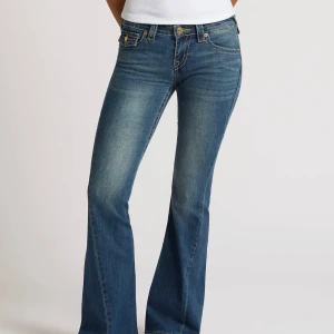 True Religion - Snygga blå jeans från True Religion med bootcut passform och klassisk femficksdesign. Jeansen har gul kontrastsöm, dekorativa ficklock bak med knapp och logopatch i midjan. Materialet är stretchigt denim för skön passform. Tyvärr för stora för mig, köpes i juni 2025💕Kan tänka mig att gå ner i pris vid snabb affär