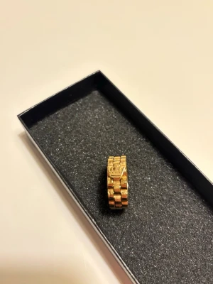 Rolex liknade ring - Snygg guldfärgad ring med den klassiska Rolex loggan. Ger en lyxig look och passar perfekt som statement-accessoar. Helt ny och oanvänd.