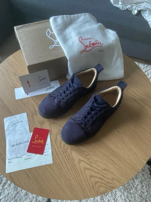 Mörkblåa Louboutin - Tjena👋 Säljer nu dessa riktigt snygga mörkblå sneakers från Christian Louboutin i mocka med klassisk röd sula😮‍💨 Skorna har rund tå, snörning och diskreta detaljer🙌 Kommer med originalkartong, dustbag och äkthetskort samt kvitto🏷️ Skick: 7/10 använda ett tag men fortfarande bra skick!🙏 