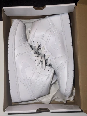 Nike Air Jordan 1 Mid Triple White - Säljer ett par Nike Air Jordan 1 Mid i helvitt skinn. Klassisk siluett med snörning, perforerad tåbox och ikoniska Jordan-detaljer på sidan. Snygga och stilrena sneakers som passar till allt. Storlek 44 (28,5 cm).