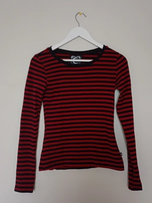 Killstar röd och svart tröja - Svart och röd randig tröja från Killstar. Tröjan är stretchig så du behöver inte oroa dig om den kommer vara för liten. Har varit använd ett par gånger men är i fint skick! 