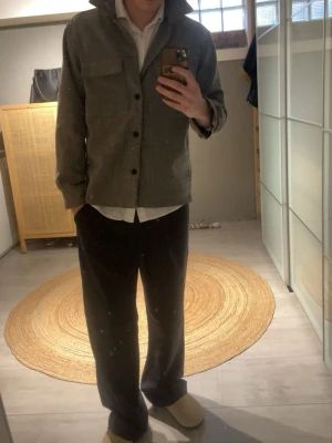 Overshirt - Stilren grå overshirt med klassisk krage och knäppning framtill. Två bröstfickor ger en schysst look och plagget har en rak passform. Perfekt att bära över en skjorta för en avslappnad men ändå uppklädd stil.