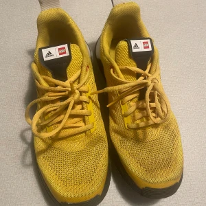 Adidas x LEGO gula sneakers strl 38⅔ - Unika Adidas x LEGO sneakers i starkt gul mesh med svarta och vita detaljer. LEGO-detaljer på häl och plös, sula med LEGO-inspirerat mönster. 