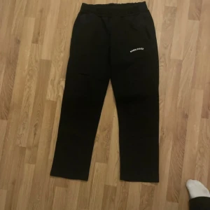 Svarta mjukisbyxor från Smilodox - Svarta mjukisbyxor från Smilodox med resår i midjan och broderad logga på ena benet. Byxorna har raka ben och är fodrade med mjukt material på insidan för extra komfort. Perfekta för chill eller träning. Storlek M men passar bäst till S