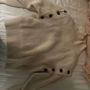 Stickad polo tröja med avtagbara armar  - Beige stickad polo tröja med bruna knappar vid armarna då man kan ta av de, storlek M ifrån H&M 