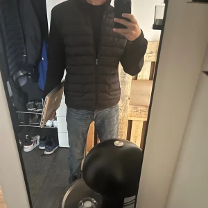 Moncler cardigan - Säljer en svart cardigan från Moncler med quiltad front och släta ärmar. Jackan har dragkedja framtill och en klassisk Moncler-logga på ärmen. Perfekt för dig som vill ha en stilren och bekväm jacka med snygg passform. Det är storlek L men skulle påstå en passar båda en M och en stor S
