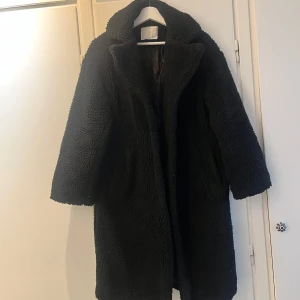 Svart teddyjacka med krage - Svart längre teddyjacka men fickor på sidan. Okänt märke ”samsa”. 
