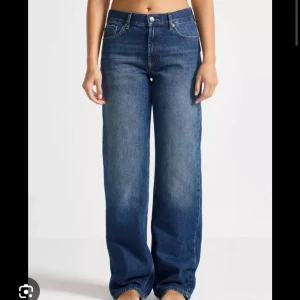 Mörkblå raka/baggy jeans  - Snygga blå jeans med breda ben. Klassisk femficksmodell i denim med raka sömmar och en cool, avslappnad passform. Perfekta för dig som gillar en trendig och bekväm stil. Jeansen har knapp och dragkedja framtill.