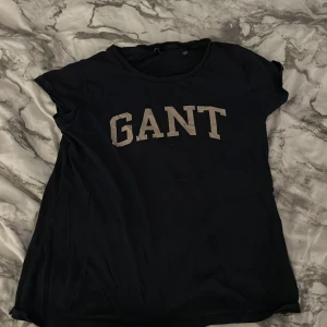 Mörkblå GANT t-shirt med tryck - Mörkblå t-shirt från GANT med klassiskt tryck i vitt över bröstet. T-shirten har rund halsringning och korta ärmar. Perfekt basic-plagg med snygg logga framtill.