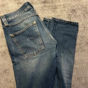 Nudie jeans  - Fina blå nudie jeans i storlek 28/32. Modell steady eddie. Defekt vid skrevet men lagat med jeansplåster. Skriv vid frågor eller funderingar!🫡