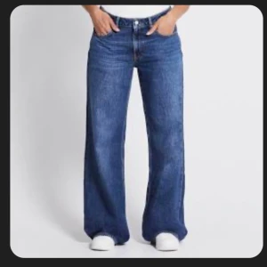 Blå optiwide jeans från 157 - Säljer ett par blå jeans från 157 med riktigt snygg wide fit och klassisk femficksdesign. Jeansen har medelhög midja och raka, vida ben som ger en avslappnad vibe. Tillverkade i klassiskt denimtyg med tydliga sömmar och läderpatch bak i midjan. Säljer då jag inte tycker att de passar mig i stil, o därför bara legat i garderob sen köpet! De är S/full lenght