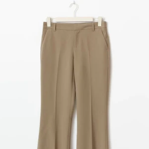 Beiga kostymbyxor med bootcut - Snygga beiga kostymbyxor med bootcut och pressveck. Byxorna har normal passform, hällor för bälte och sidfickor. Perfekta för en clean och stilren look. Materialet känns mjukt och har en lätt stretch för extra komfort. Priset går att diskutera vid snabbare affär 