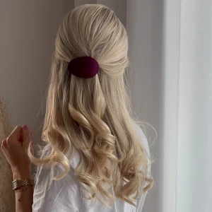 Vinröd hårklämma i tyg - Säljer en ovalformad hårklämma i vinrött tyg med metallspänne. Perfekt för att sätta upp halva håret och ge en snygg detalj till frisyren. Klämman är klädd i ett mjukt tyg som ger en stilren och trendig look. Gjort av återvunnet tyg och återvunna skedar 