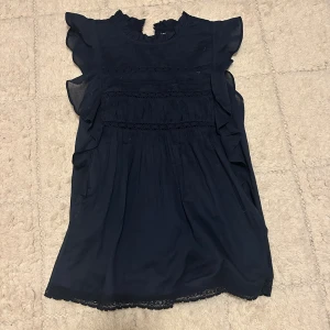 Mörkblå blus - Supersöt mörkblå blus från Holly & Whyte med volangdetaljer på axlarna och spetsinslag. Perfekt för dig som gillar romantisk och luftig stil. Passar mig som är s/m.