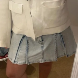 Ljusblå jeanskjol med sömmar - Säljer en ljusblå jeanskjol med markerade sömmar och lätt utsvängd form. Kjolen är kort och har en cool, ungdomlig vibe med paneler som ger extra struktur. Perfekt att matcha med sneakers eller boots för en chill look.