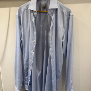 Ljusblå skjorta från Lachen - Säljer en stilren ljusblå skjorta från La Chemise i storlek L (42). Med extra lång arm. Skjortan har klassisk krage, långa ärmar och vita knappar framtill. Perfekt för dig som gillar en clean och enkel look. Materialet är mjukt och känns skönt mot huden.
