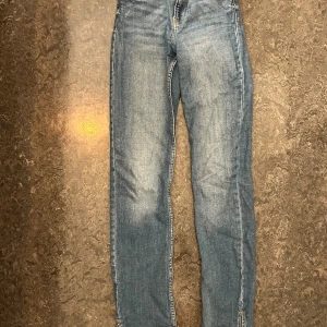 Blå Bershka jeans  - Snygga blå jeans från Bershka med high waist och klassisk femficksdesign. Jeansen har raka ben och är tillverkade i denim med ljus tvätt och subtila slitningar med öppning vid fotleden. 