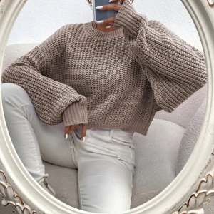 Beige stickad tröja - Säljer en beige stickad tröja med grov ribbstickning och croppad passform. Tröjan har rund halsringning och långa ärmar med breda muddar. Perfekt för lager-på-lager och chill höstoutfits.