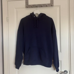 Mörkblå hoodie från BikBok - Säljer en mörkblå hoodie från BikBok i storlek S. Hoodien har huva med snörning, stor magficka och långa ärmar. Modellen är loose fit och passar perfekt för chill dagar. Materialet är mjukt och känns skönt mot huden.