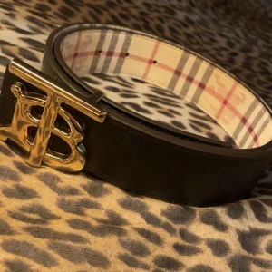 Burberry svart och rutig skärp - Säljer ett snyggt Burberry bälte i storlek 110cm men finns många hål satt borde passa dem flesta. klassiskt rutigt mönster på insidan och svart på utsidan. Går att använda båda som ni ser på bilderna. Säljer det för att det är inte riktigt min still och har bara använts 1 eller 2 gånger. Kom gärna privat med frågor! Pris kan diskuteras!🫶