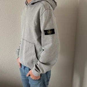 Grå Stone Island hoodie  - Säljer en grå hoodie från Stone Island med klassisk patch på ärmen. Storlek 170, men sitter som S. Har lite flaws (se bild 3), men inget man tänker på och är i bra skick i övrigt. 8/10 skick. bara att höra av sig vid frågor! Nypris: 2149kr