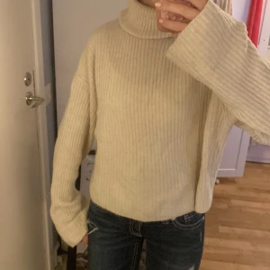Beige ribbad polotröja med vida ärmar - Säljer en beige ribbstickad polotröja med oversized passform och långa, vida ärmar. Tröjan har hög polokrage och är gjord i ett mjukt, stickat material som är perfekt för kyliga dagar. Enkel att styla med jeans eller kjol, använt ganska många gånger så den är lite nopprig💕