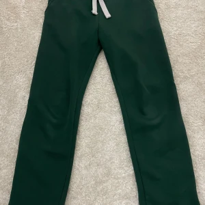 Gröna Russemerch  - Mörkgröna mjukisbyxor från Russemerch i storlek S. Byxorna har en bekväm resår i midjan och vita snören för justering. Tillverkade i mjukt material som passar perfekt för chill eller träning. Klassisk rak passform och enkel design. Inga skavanker och i mycket bra skick