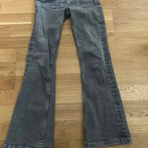 Grå bootcut jeans från Gina Tricot - Snygg a grå jeans från Gina Tricot i storlek 134. Modellen har klassiska fem fickor, silverfärgad knapp och ett bootcut-snitt som ger en cool retrovibe. Jeansen är tillverkade i mjukt denimtyg och har en normal passform med raka ben som blir vidare nedtill.
