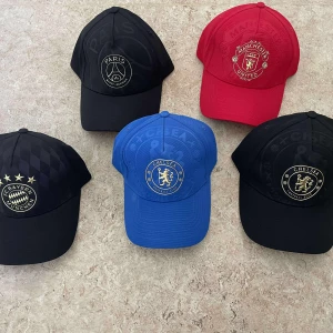 Kepsar med fotbollslag-loggor - Snygga kepsar med broderade loggor från Manchester United, Chelsea, PSG och Bayern München. Finns i svart, röd och blå. Klassisk form med böjd skärm och justerbar passning. Perfekt för dig som vill visa vilket lag du supportar.