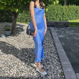 Blå långklänning i satin med smala axelband - Säljer en stilren blå långklänning i satin med smala axelband och mjukt fall. Använd endast en gång i några timmar, helt ny. Passar för bal, fest osv.