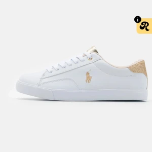Vita sneakers från Polo Ralph Lauren - Stilrena vita sneakers med gulddetaljer från Polo Ralph Lauren. Skorna har snörning, rund tå och en glittrig guldpanel vid hälen. Märkets ikoniska logga i guld syns på sidan och plösen. Perfekta för en fräsch och sportig look.
