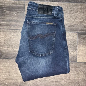 Nudie Jeans  - Snygga Skinny Lin jeans från Nudie Jeans i mörkblå tvätt med klassiska bakfickor och diskreta slitningar. Modellen är slim fit med raka ben och tillverkad i 99% ekologisk bomull och 1% elastan för extra stretch. Midja 37cm, längd 111cm. Ifall det inte finns någon bild i annonsen där jag bär plaggen jag säljer så är det för att jag ej kan ha storleken heller passformen, så kolla måtten för storlek och googla på modellnamnet för passform 😉 s2