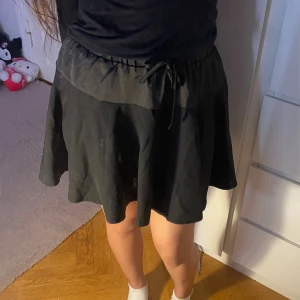 Svart kjol  - Söt svart kjol med resår och snörning i midjan. Fluffig och lätt tyg som ger ett fint fall – perfekt både till vardag och fest! Storlek: S Mycket fint skick ✨  🖤 Enkel att styla med croptop, skjorta eller stickad tröja för olika looks.